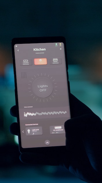 Foto persona che controlla la luce della casa utilizzando lo schermo tattile dell'applicazione smart home per accenderla dal telefono cellulare