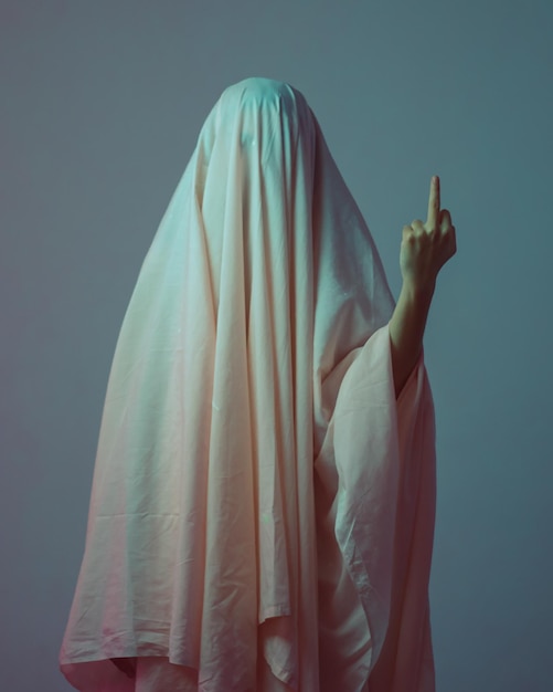 Photo person covered with fabric showing middle finger against gray background