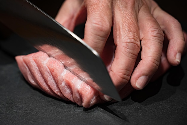 A person cutting a piece of meat with a knife