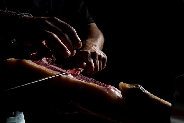 A person cutting a piece of meat with a knife