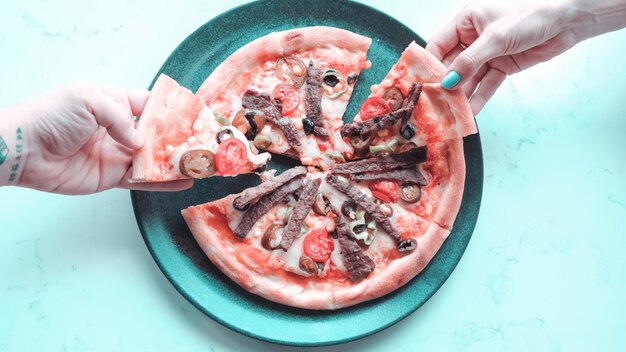 Photo a person cutting a pizza with a knife and a knife