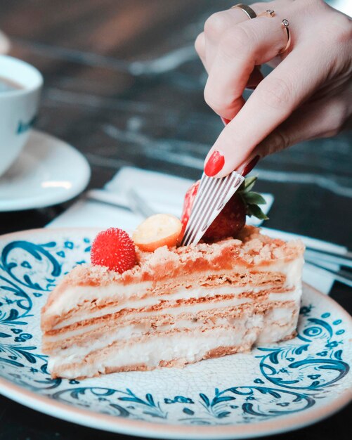 a person cutting a slice of cake with a fork