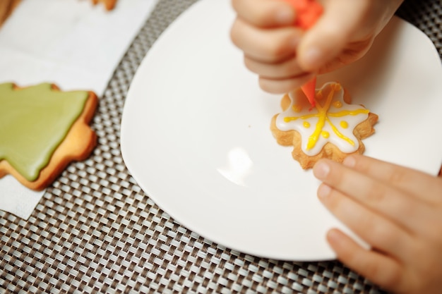 Person decorating freshly baked gingerbread cookies with icing