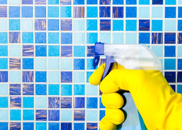 Photo person doing chores in bathroom at home spraying disinfectant fluid on a wall a protective measures against coronavirus spreading and contamination