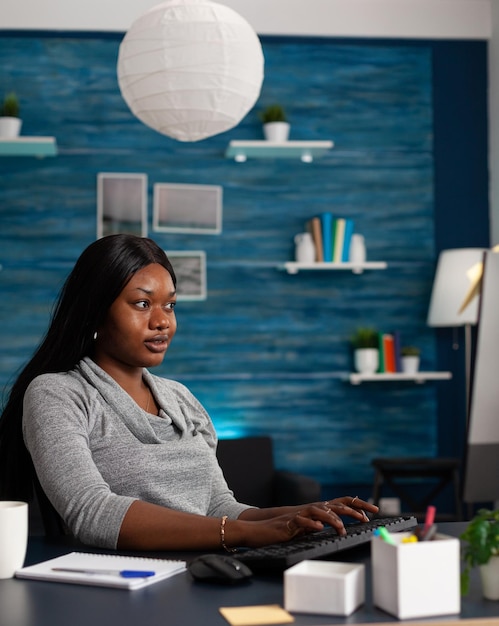 Person doing remote work using computer with keyboard. Smiling woman using monitor and internet connection, working online on business project at home office. Freelance employee at desk