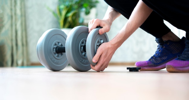 Person doing workout and put on a weght disc on a barbell dumbbell