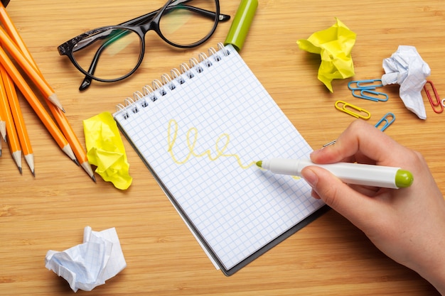 Person drawing in a notepad and office supplies on the table