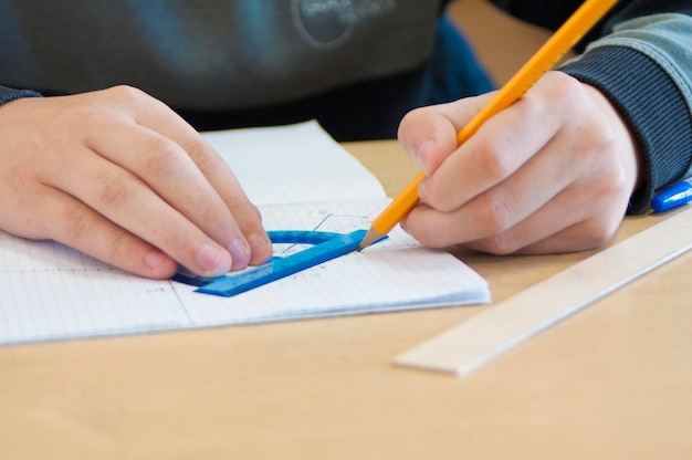 A person draws with a ruler and a transparency