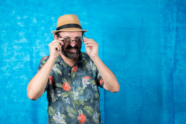 Person dressed as a tourist with a printed shirt and a face of astonishment and taking off his glasses