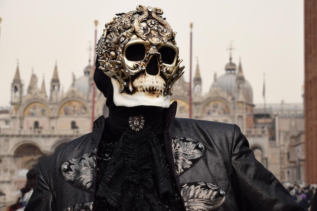 Person dressed up for Carnival of Venice wearing skull mask and black suit