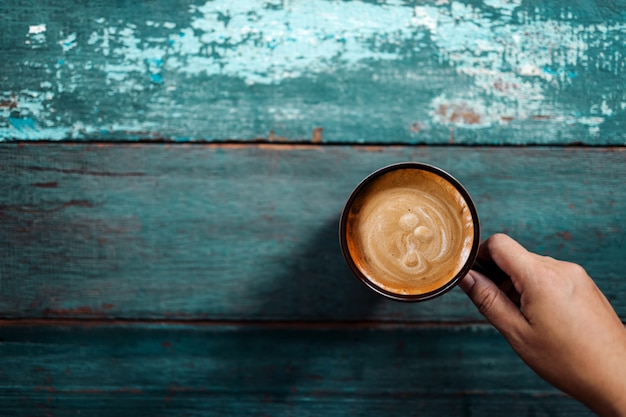 Persona che beve caffè sulla vecchia tavola blu