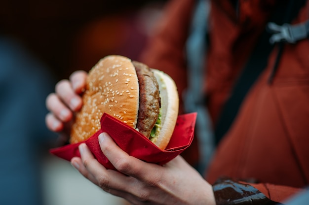 Persona che mangia un grande hamburger