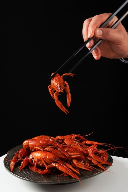 Person eating crawfish with chopsticks