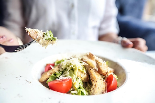 person eating salad with fork at outdoor cafe table