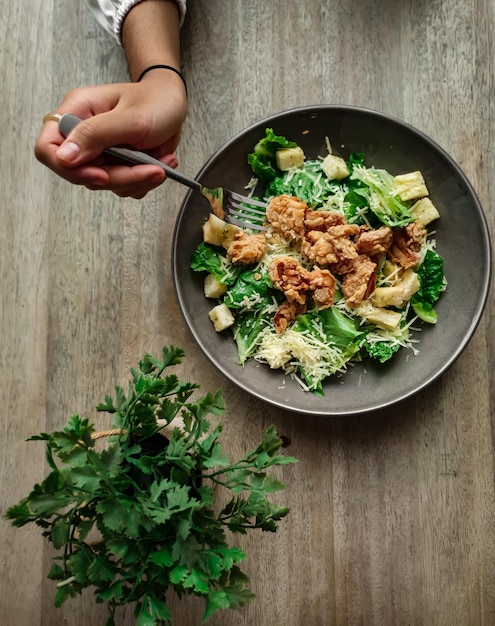 Foto una persona che mangia un'insalata con una forchetta.