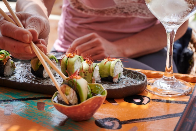 Photo a person enjoying a healthy and fresh japanese sushi meal served with chopsticks