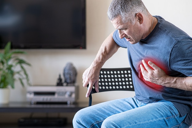 Photo a person experiences chest pain caused by a heart attack. heart disease. angina pectoris. the concept of health insurance for the elderly.