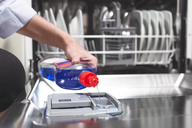 Photo person filling dishwasher with gloss liquid into the dishwasher box