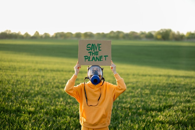 Photo person in gas mask holds cardboard with a call to save the planet