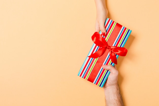 Person gives gift box with red bow