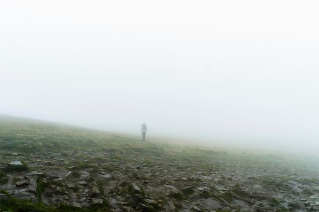 Photo person on grassy hill against clear sky during foggy weather