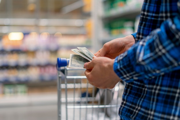 A person in a grocery store, hands count the money currency