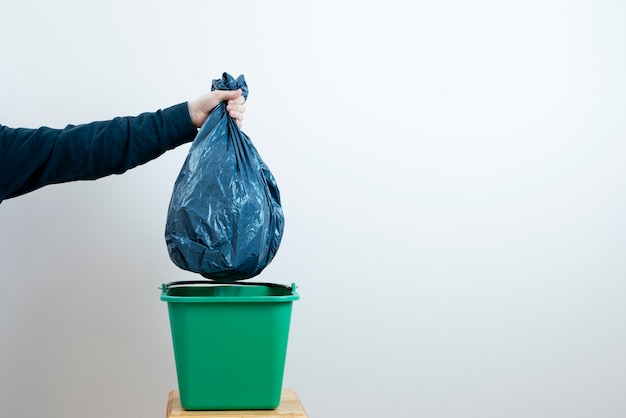 Рука человека бросает мусор в мусорное ведро