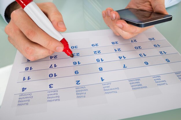 Person Hand Holding Marker Over Calendar