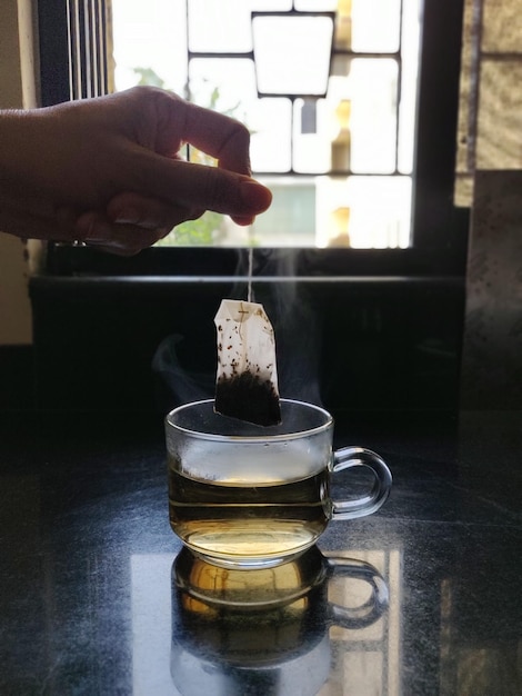 Фото Человек с рукой, держащей чашку чая на столе