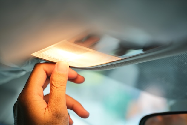 Photo person hand turn on the reading lamp inside his car