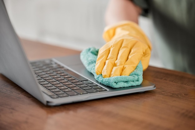 Person hands and cleaning laptop for disinfection bacteria or germ removal on wooden table at home Closeup of housekeeper cleaner or maid wiping computer in sanitizing hygiene or clean equipment