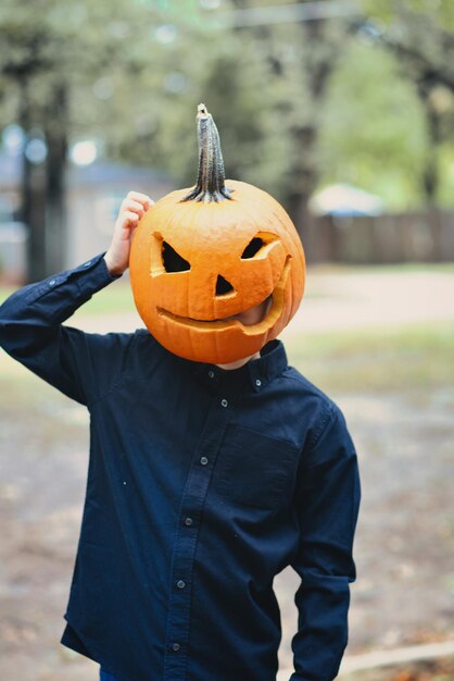 Photo person having fun with a carved pumpkin head