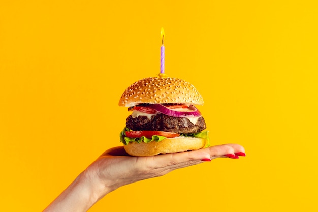 Foto persona in possesso di un hamburger dell'anniversario