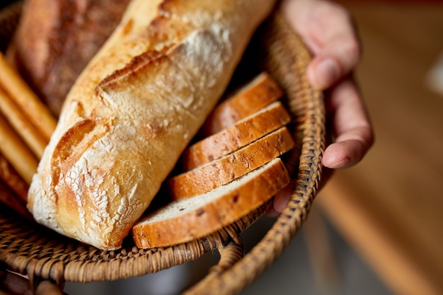 Person holding basket with various breads freshly baked