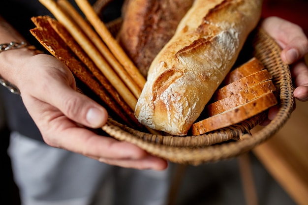 Person holding basket with various breads freshly baked