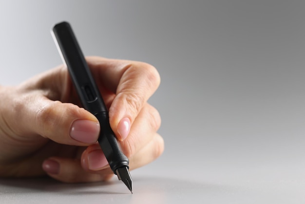 Person holding black feather pen sharp tip tool for writing