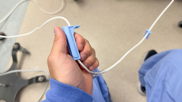 A person holding a blue plastic device with a white cord attached to it.
