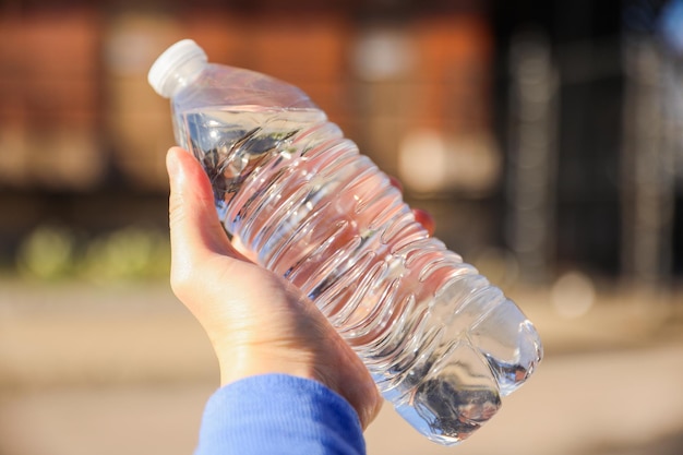 A person holding a bottle of water in their hand.