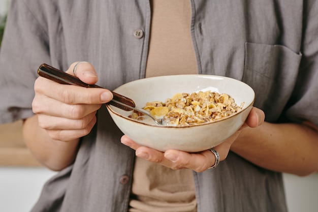 A person holding a bowl of corn flakes during breakfast