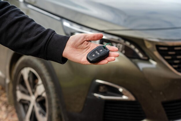 Person holding a car key in the hand stands front car Insurance loan and buying car concept