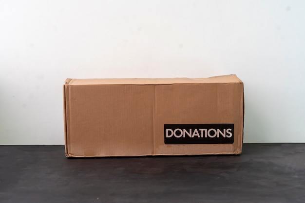 A person holding a cardboard box with a donation word, charity volunteer delivery