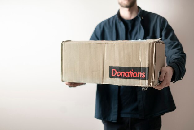 A person holding a cardboard box with a donation word, charity volunteer delivery