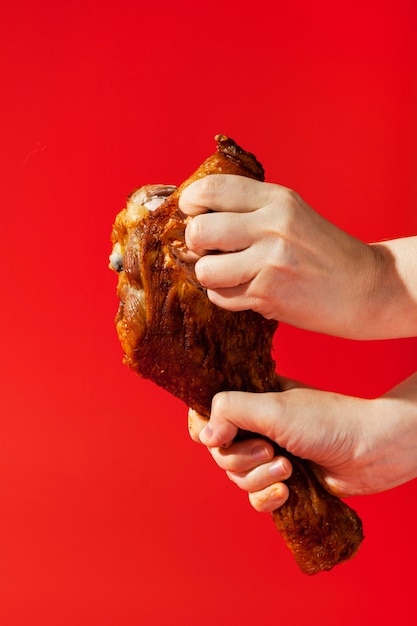 Person holding a chicken leg and breaking a piece of it