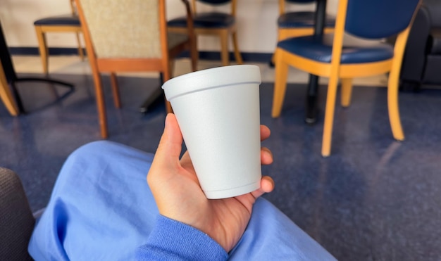 A person holding a cup of coffee in a hospital room.