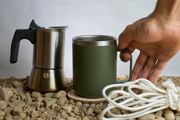 Foto persona che tiene una tazza di caffè su un sito roccioso con persona sullo sfondo grigio