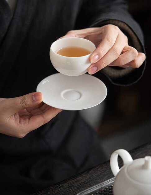 A person holding a cup of tea from the teapot