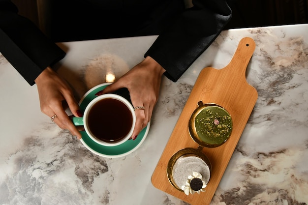 Photo a person holding a cup of tea and a wooden tray with a green tea on it.