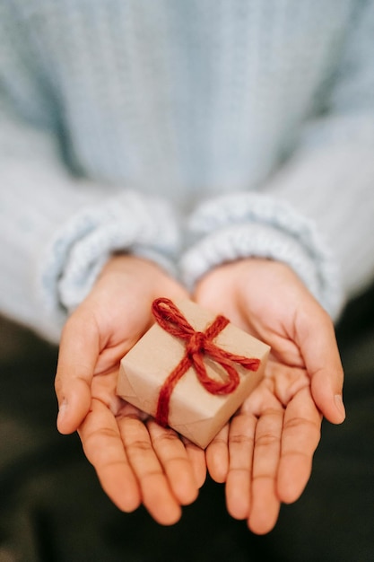 Foto una persona che tiene un regalo con un nastro rosso nelle mani