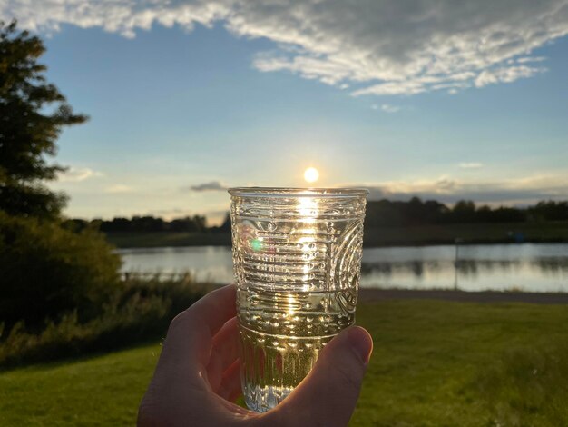 Person holding glass against lake