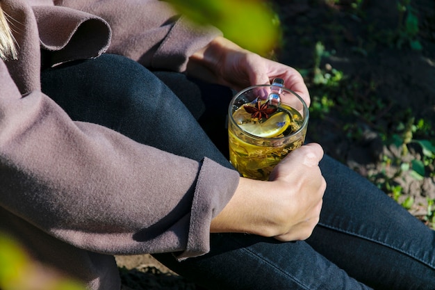 Person holding a glass cup with herbal tea